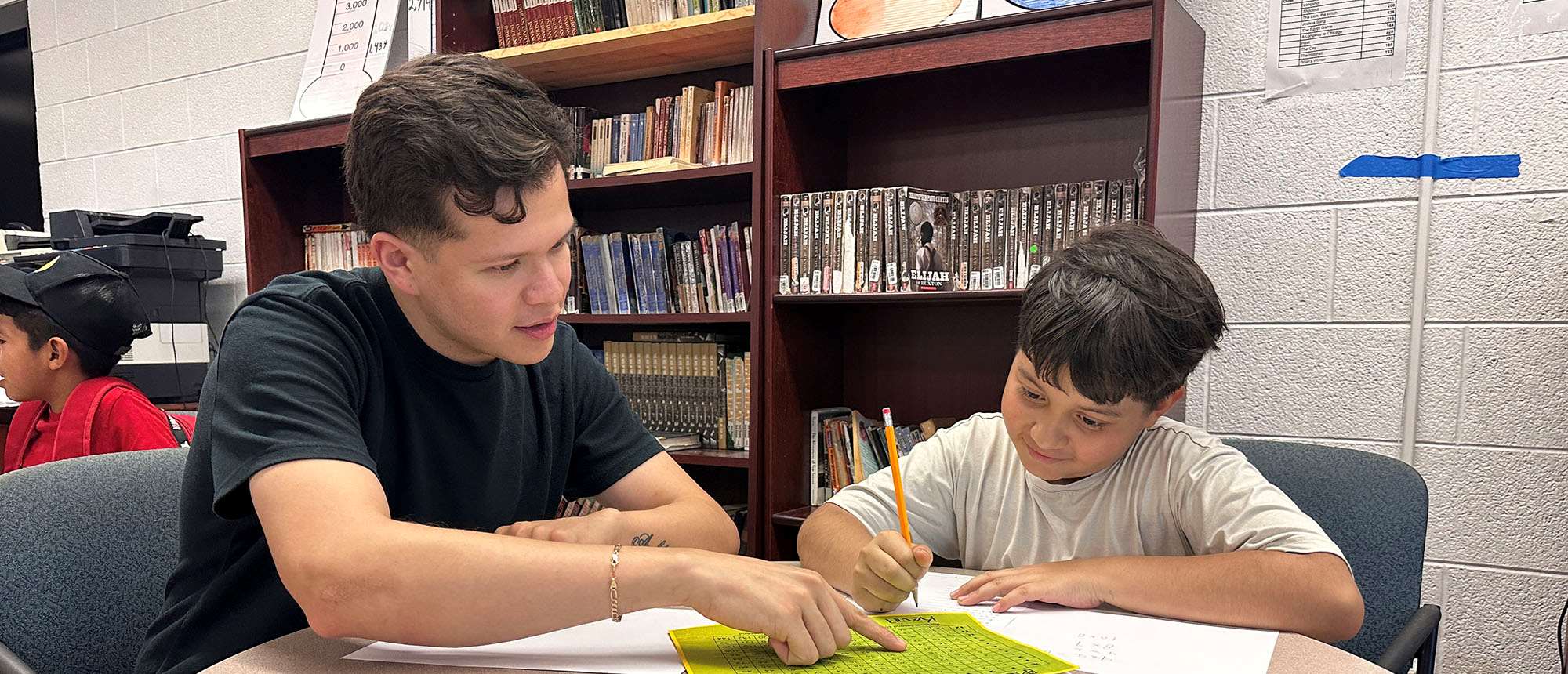 Justin Perez assisting young boy with studies