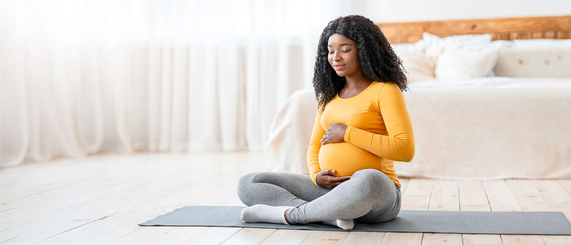 Pregnant woman sitting on a floor mat