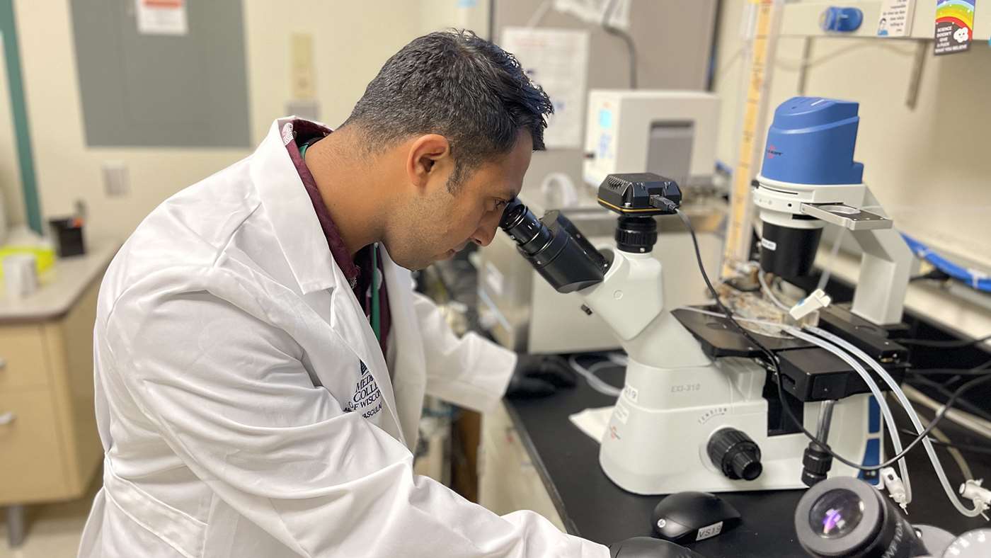 Cristhian Gutierrez Huerta looking through microscope