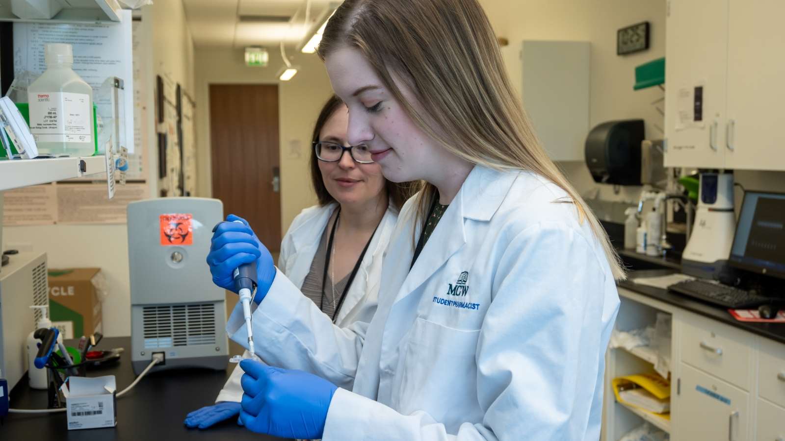 Pharmacy student works in a laboratory setting alongside her preceptor.
